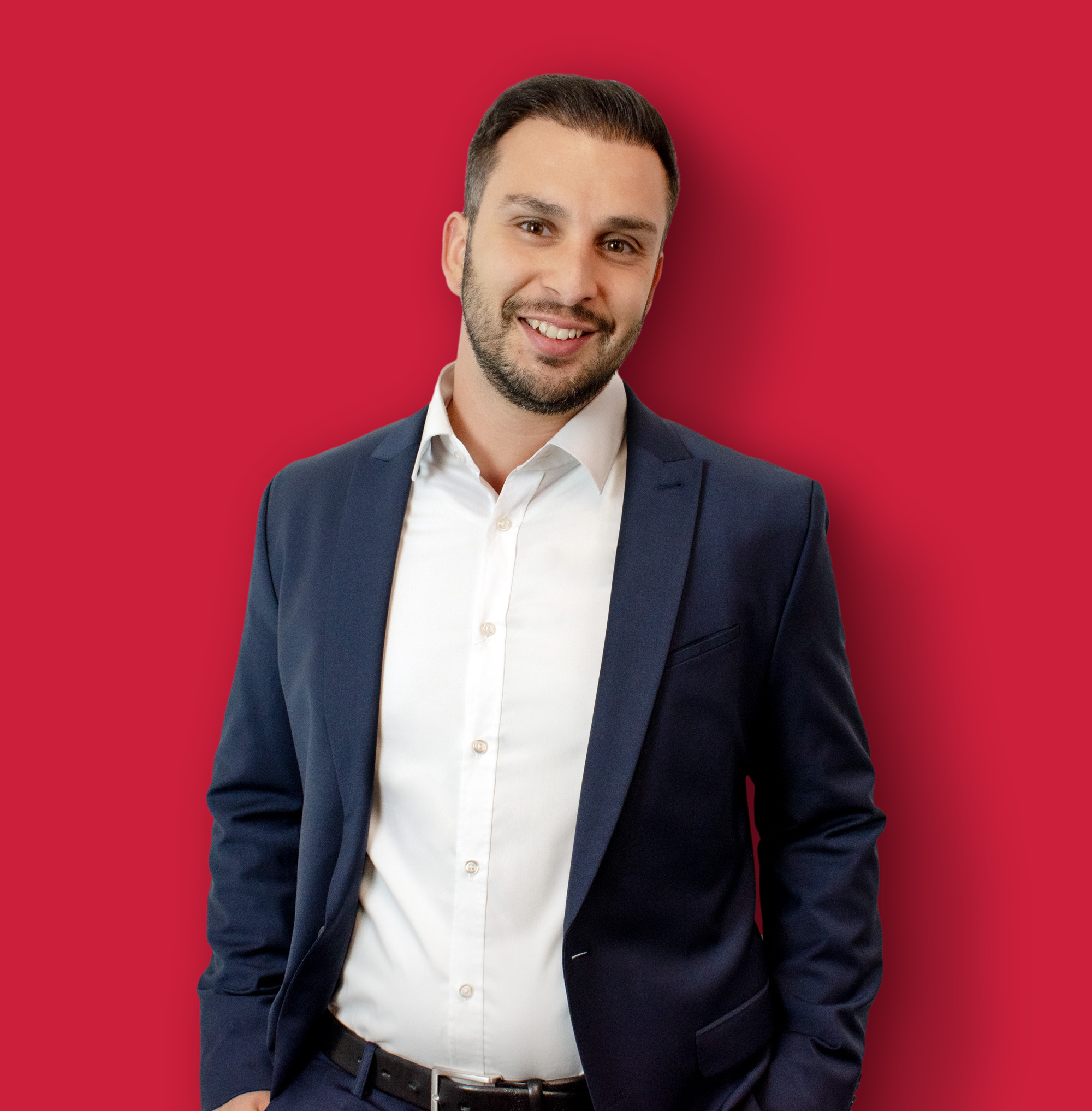 Porträtfoto des Business Coaches Ali Tumani vor rotem Hintergrund.